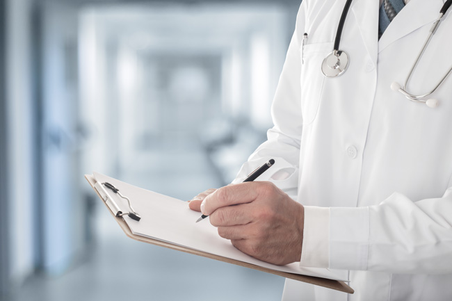 Healthcare worker writing on a clipboard, whose office uses Optima's fractional CFO services Healthcare worker writing on a clipboard, whose office uses Optima's fractional CFO services